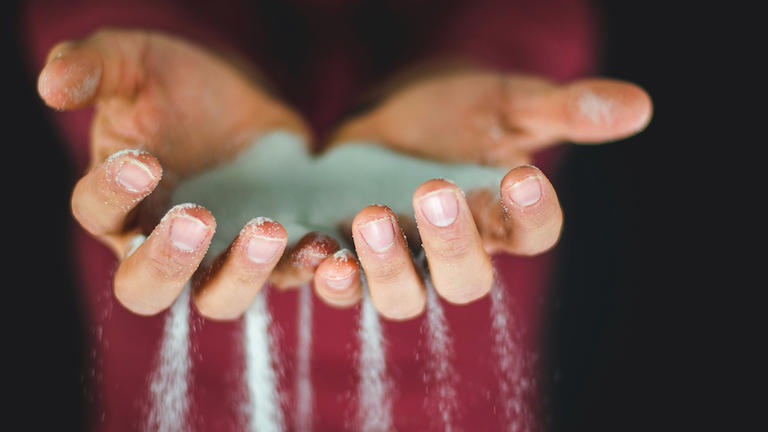 Two hands holding sand that is falling through the fingers