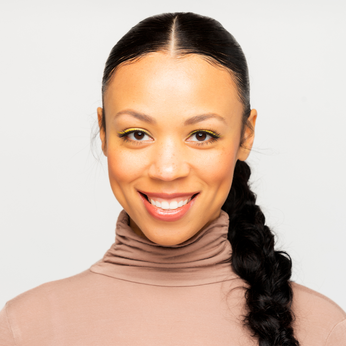 Nicole color portrait. Nicole is a Black woman who is smiling in this portrait. Her hair is braided and off to one side. She is wearing a light-tan turtleneck.