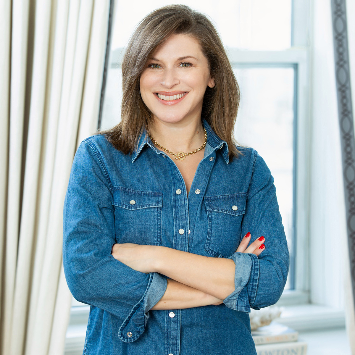 Jennifer N. Levin color portrait. Jennifer is standing with her arms crossed and she has brown medium-length hair and is wearing a jean top.