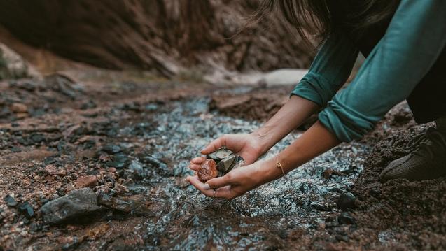 Woman in the stream holding rocks