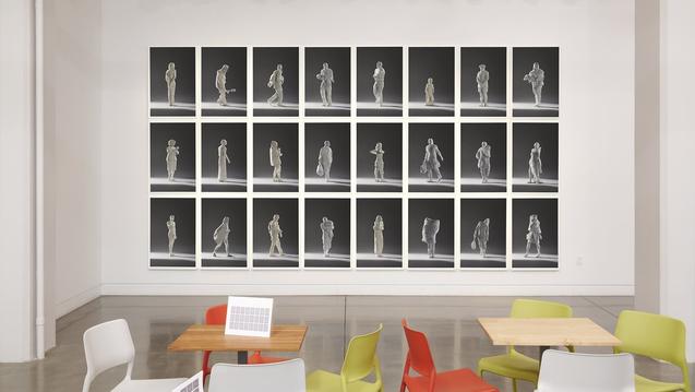 Photo of an art gallery wall with rows of photos hung and cafe tables