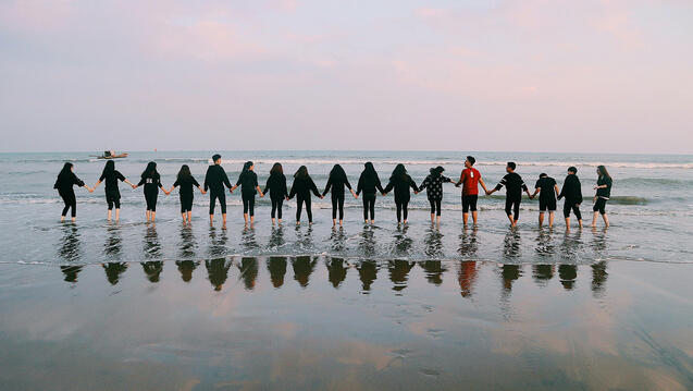 Photo of people standing in a row on a beach