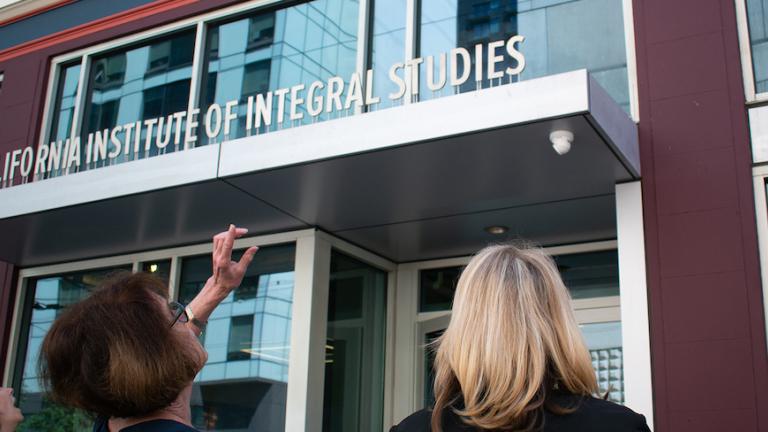 Two CIIS staff members standing in front of CIIS main campus building.