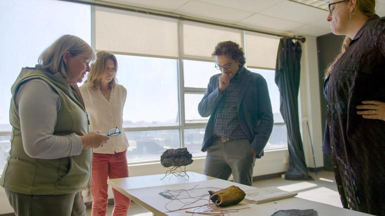 Photo of people looking at artifacts on a table