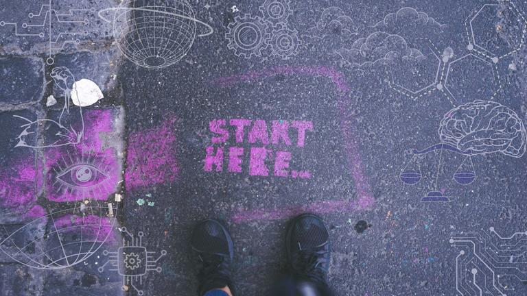 Sidewalk art with Start Here written in purple