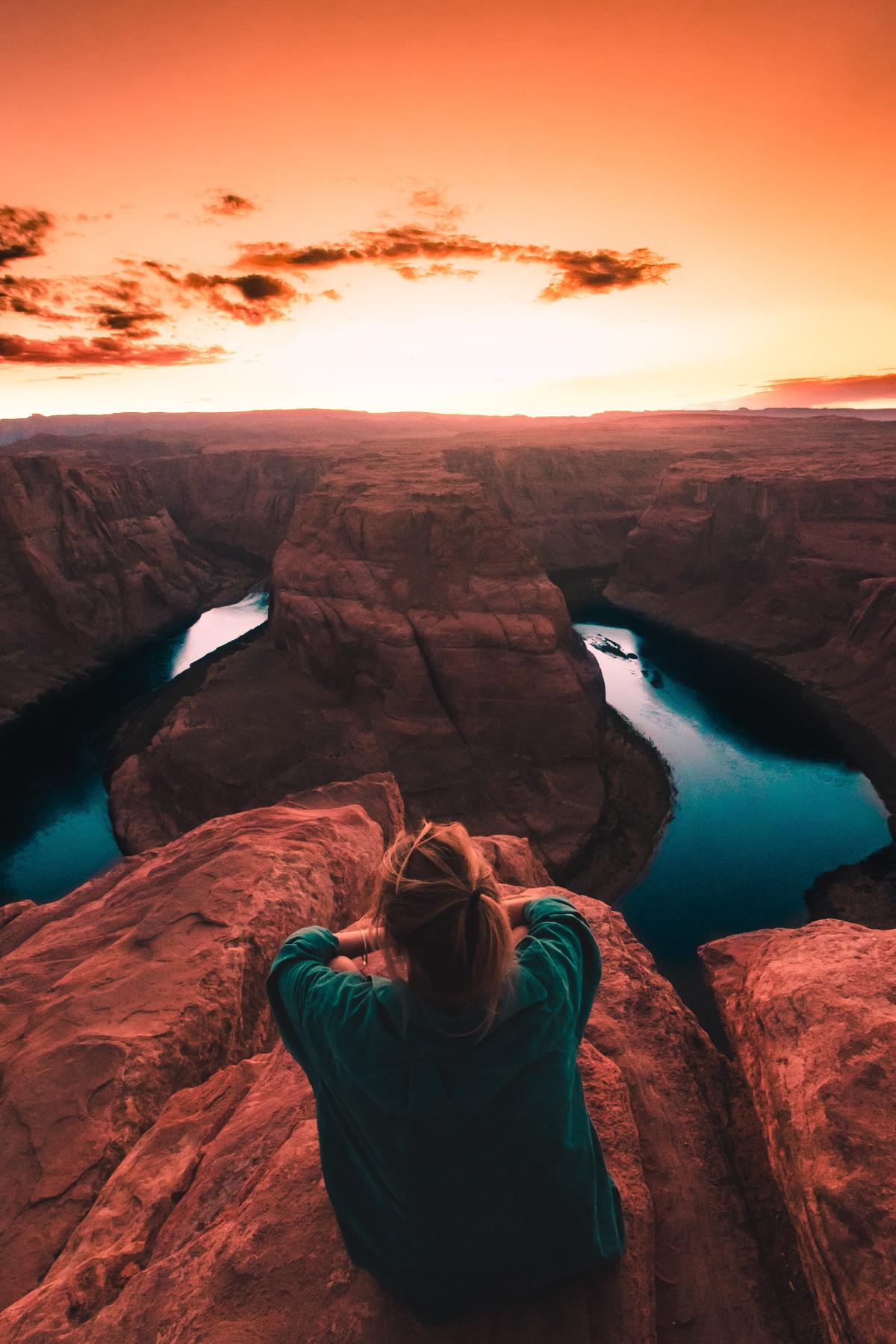 Person looking out over a mountain ravine at sunrise.