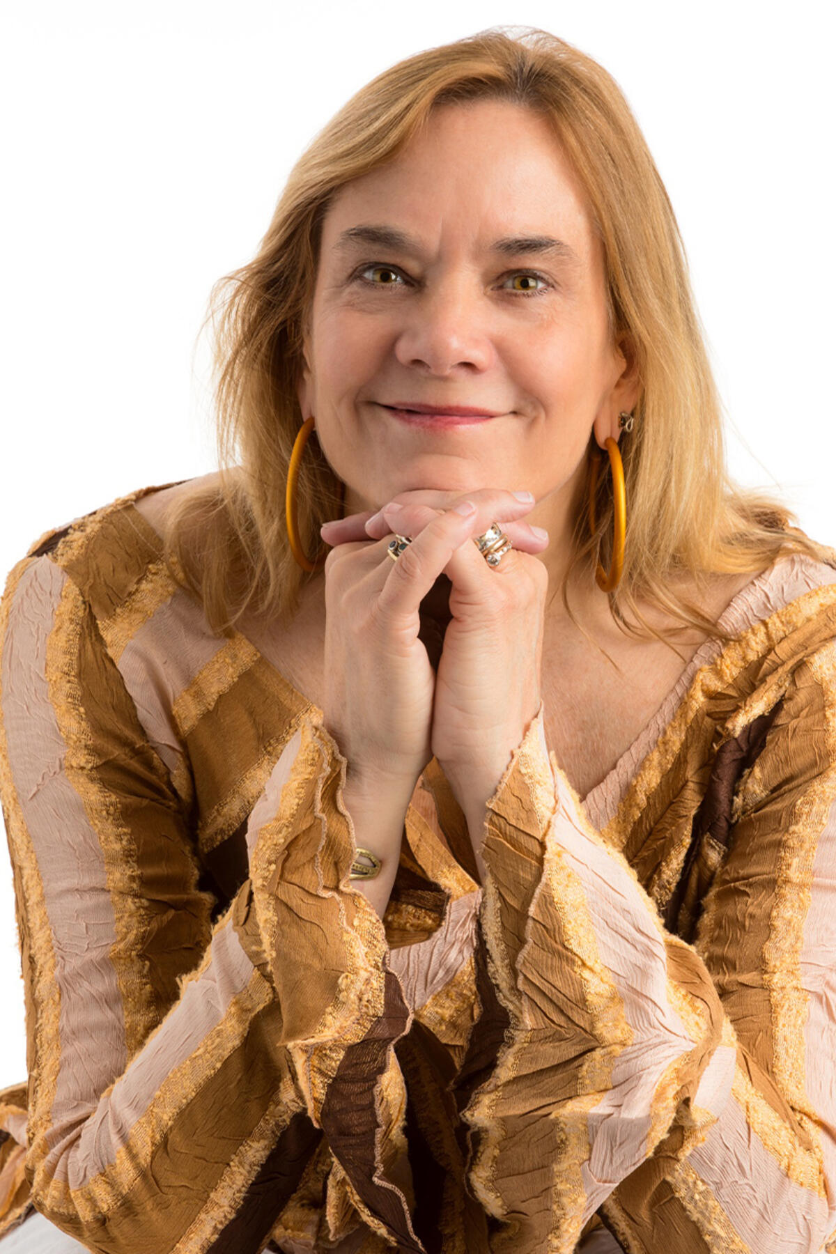 Amber Elizabeth Gray color portrait. Amber is a white woman with blonde hair and is seated. Her embows are bent and rested on her knees and her hands are interlaced and her chin rests on her hands.