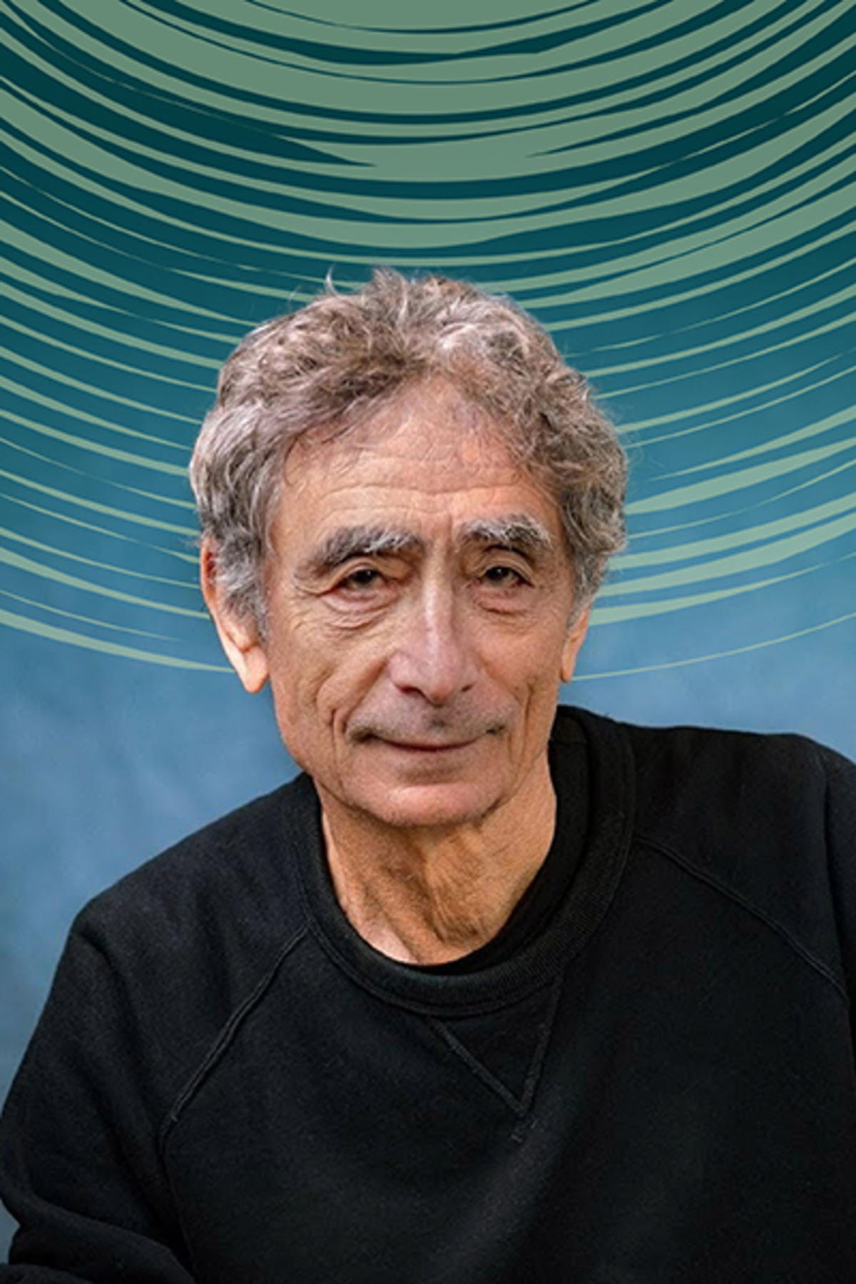Dr. Gabor Maté color portrait. Dr. Maté is a Canadian-Hungarian older white man who is posed in front of a soft blue background and is wearing a dark-colored sweatshirt.
